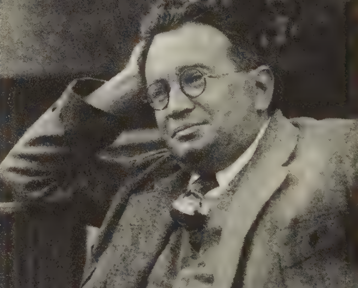 A white man wearing glasses and a suit is sittingA white man wearing glasses and a suit is sitting